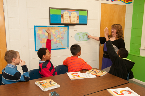 Academy Teacher with Students Looking at a Map